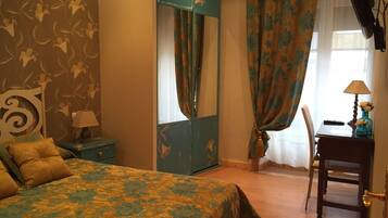 A bedroom with a bed, a dresser, a desk with a lamp, and a chair.