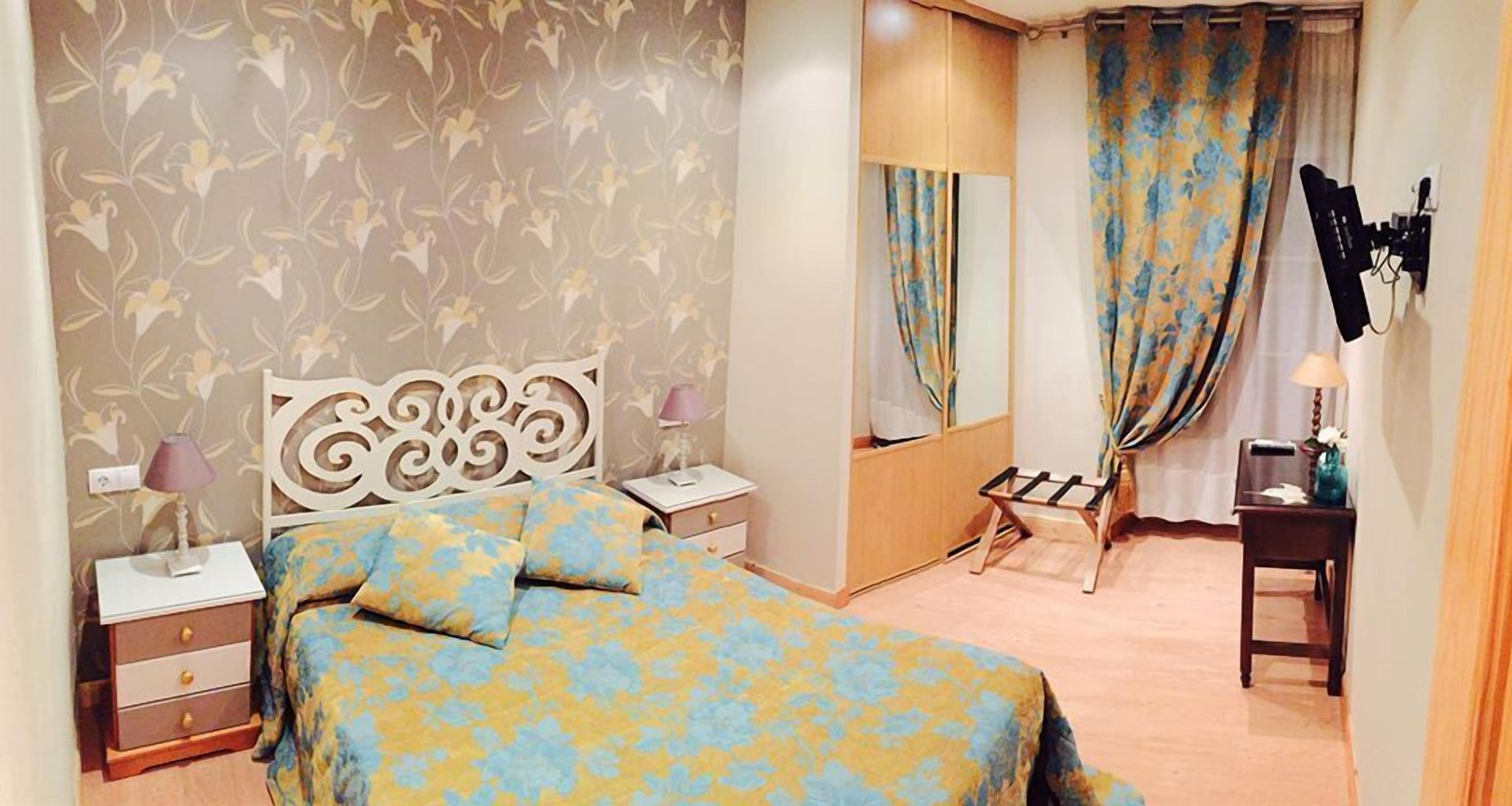 A bedroom with a bed, nightstands, a dresser, a mirror, and a vanity with a lamp.