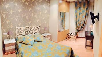 A bedroom with a bed, nightstands, a dresser, a mirror, and a vanity with a lamp.