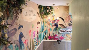 Een muur met een bloemenmuur en een bordje met de tekst 'Hostería Villa de Castro KAMERS'.