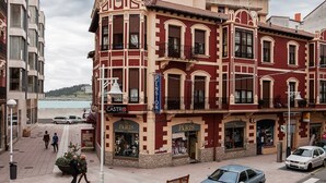Een gebouw met een gevel in rood en beige, met winkels met de aanduiding 'Paris' en 'Castro'.