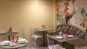 Un interior de restaurante con mesas redondas, sillas transparentes y un mural en la pared.
