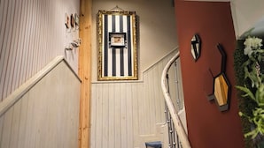 Een trap met een gestreepte muur, een lijst met een foto en een wandlamp.