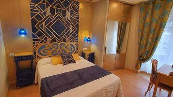Una habitación de hotel con cama, escritorio, silla, un muro decorativo y ventana con cortinas.