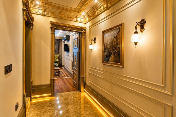A hallway with a marble floor, ornate wall decorations, and a painting. - Real King Residence  (Yomra)