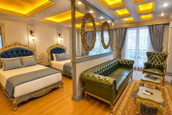 A luxurious bedroom with two ornate beds, a green leather sofa, and a classic armchair. - Real King Residence (Yomra)