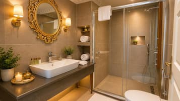 Un baño moderno con un espejo grande, un lavamanos blanco, cabina de ducha y un inodoro.
