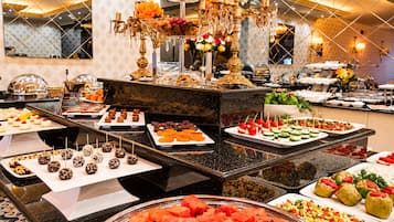 Een buffet met diverse gerechten, waaronder fruit, desserts en voorgerechten.