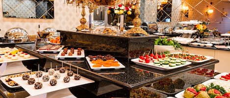 A buffet with various food items, including fruits, desserts, and appetizers.