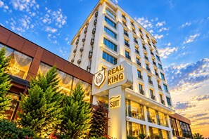 A multi-story hotel with a prominent Real King Suit sign, large windows, and a modern architectural design. - Real King Residence  (Yomra)