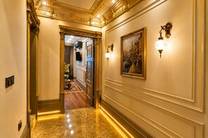 A hallway with a marble floor, ornate wall decorations, and a painting. - Real King Residence (Yomra)