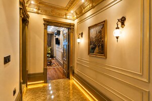 Un pasillo con piso de mármol, decoraciones ornamentales en las paredes y un cuadro.