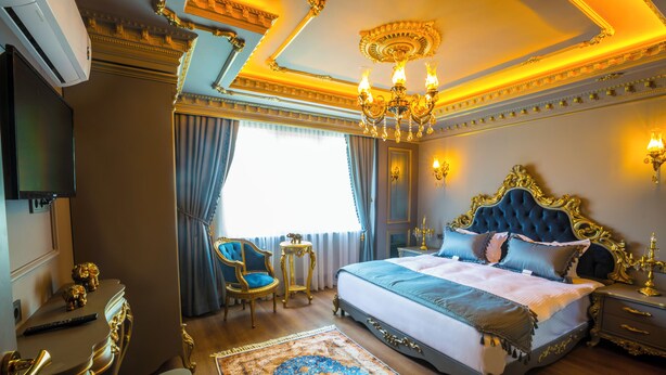 A luxurious bedroom with a large bed, ornate ceiling, and a chandelier. - Real King Residence  (Yomra)