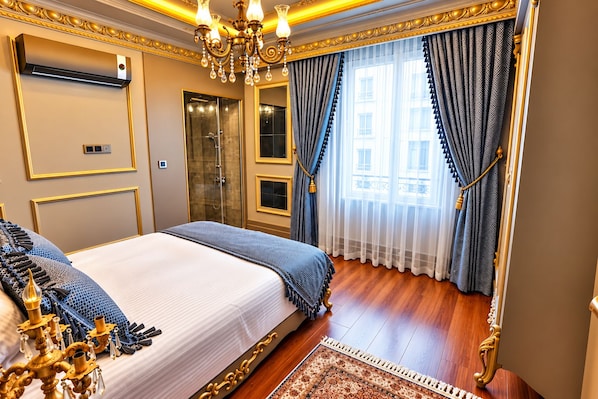 A luxurious bedroom with a large bed, a chandelier, a shower, and a view of the city.
