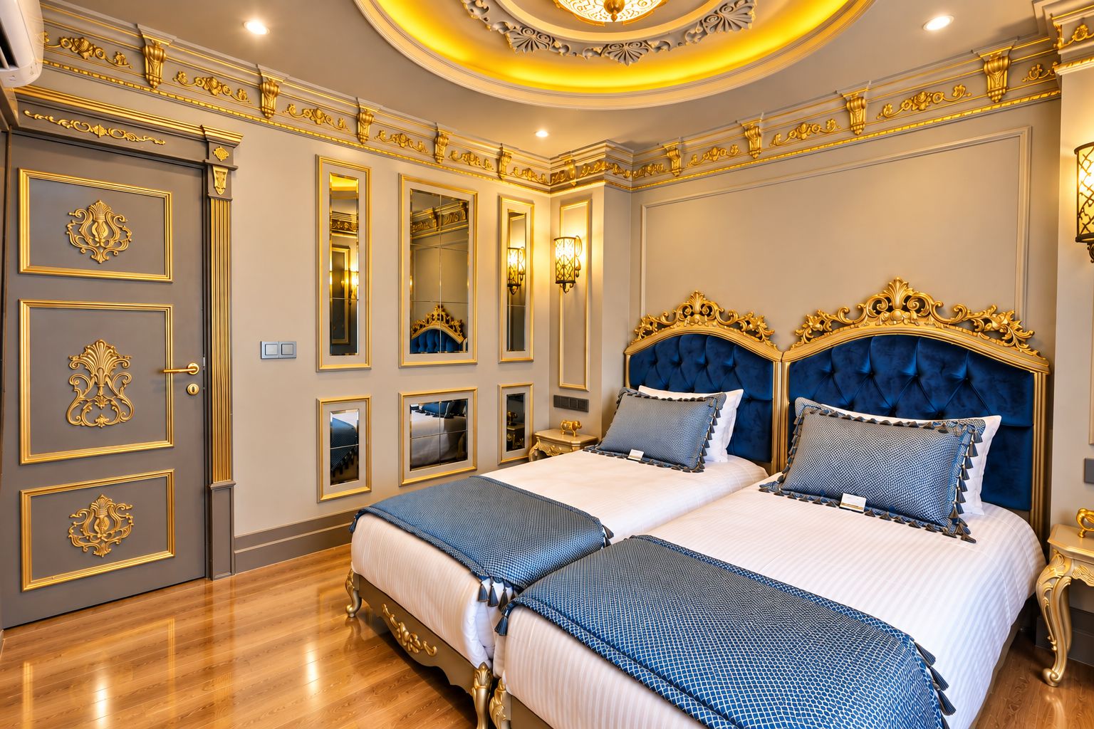 A luxurious bedroom with two beds, ornate gold detailing, and a mirror wall.