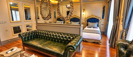 A luxurious room with a green leather sofa, a bed with a blue headboard, and ornate mirrors.