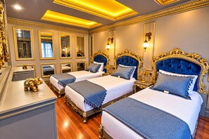 A luxurious hotel room with three beds, ornate gold detailing, and a large mirror. - Real King Residence  (Yomra)