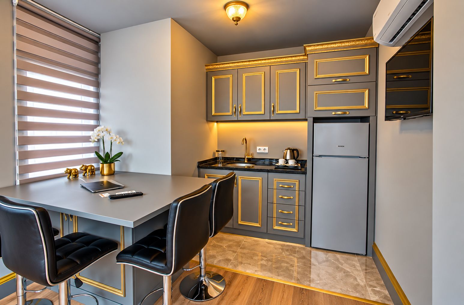 Una cocina moderna con comedor, que incluye una isla de cocina, taburetes de bar y un refrigerador.