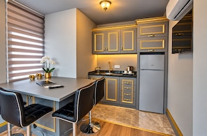 Una cocina moderna con comedor, que incluye una isla de cocina, taburetes de bar y un refrigerador.