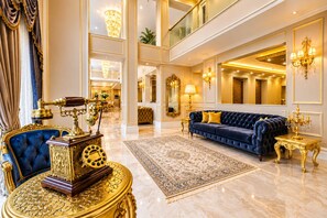 A luxurious interior with a grand chandelier, a plush blue sofa, and a classic desk with a vintage telephone. - Real King Residence  (Yomra)