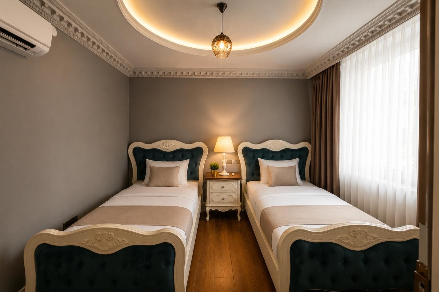 A hotel room with two beds, a nightstand with a lamp, and a ceiling light fixture.