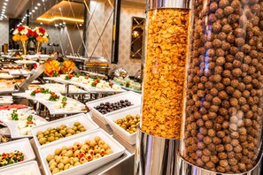 A buffet with various food items including olives, meatballs, and cereal. - Real King Residence (Yomra)