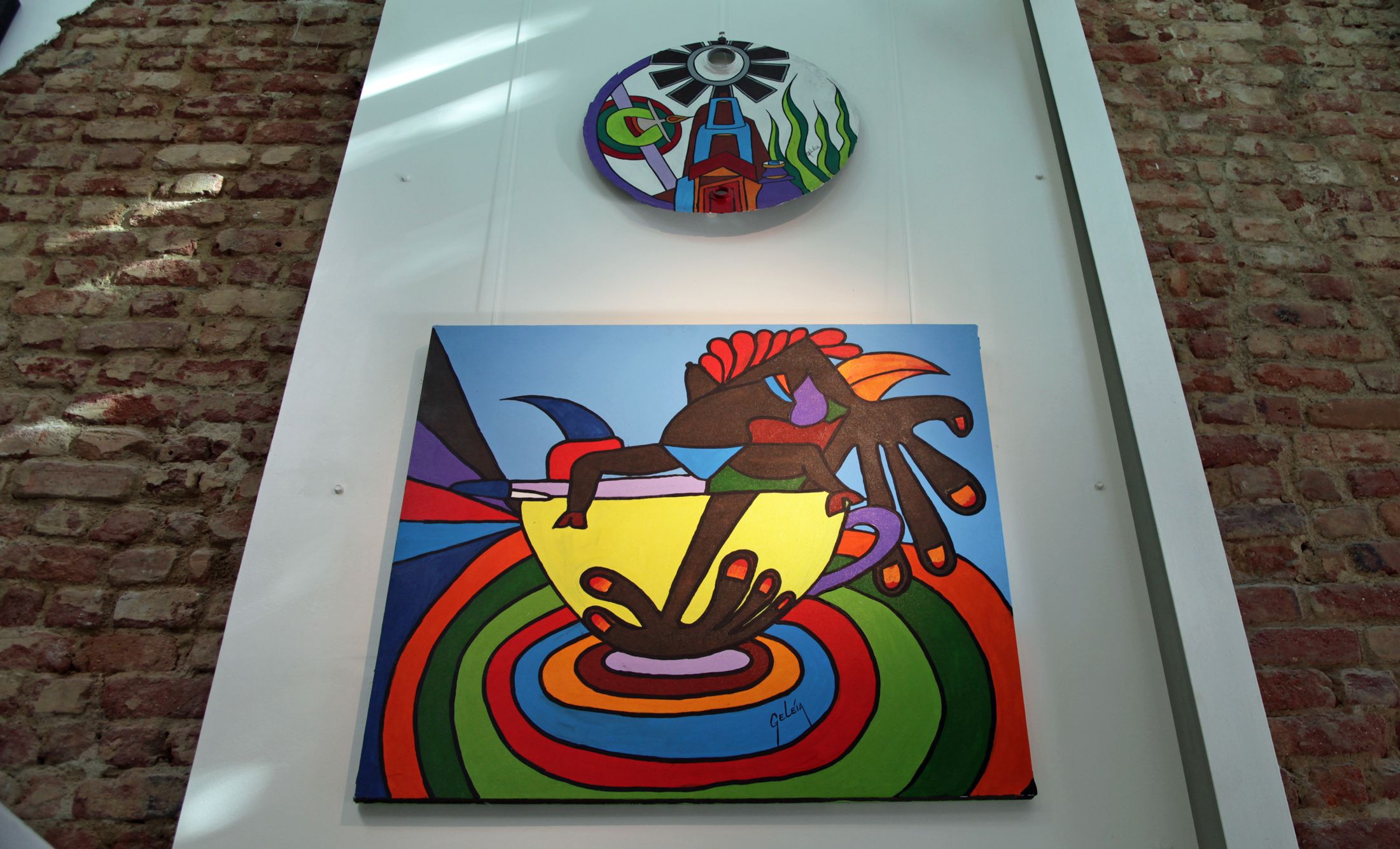 Une fresque murale aux motifs abstraits et colorés, représentant une main tendue vers un bol.
