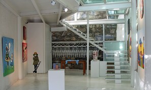 Une galerie d’art avec un escalier, des tableaux et des sculptures.