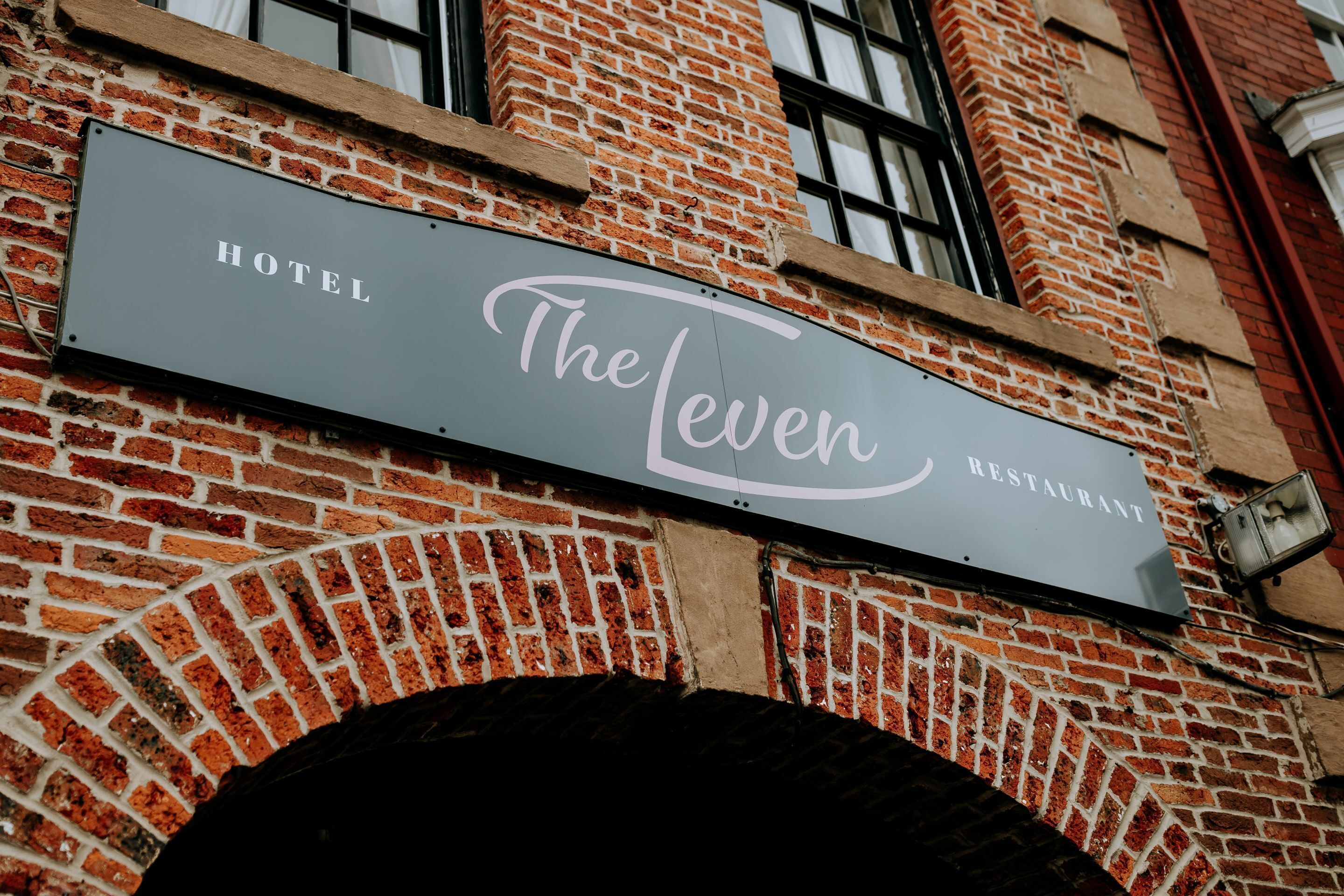 Tiilitalon seinässä oleva kyltti, jossa lukee: ”The Leven Restaurant”.