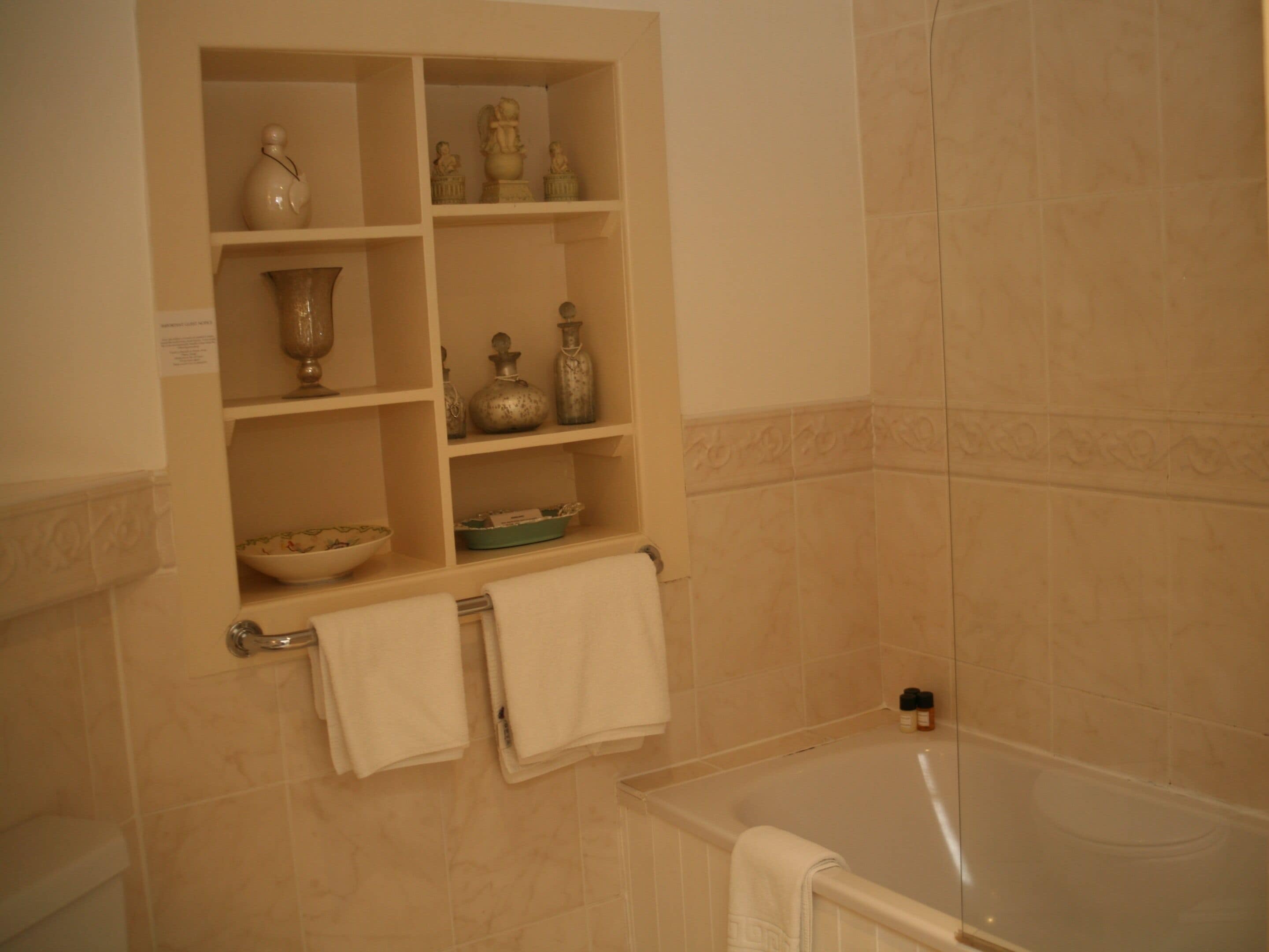 A bathroom with a bathtub, shelves with toiletries, and a towel rack.