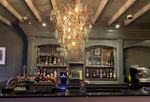 A bar area with a unique chandelier, shelves of liquor bottles, and a bar counter with taps. - OYO The Leven (Middlesbrough)