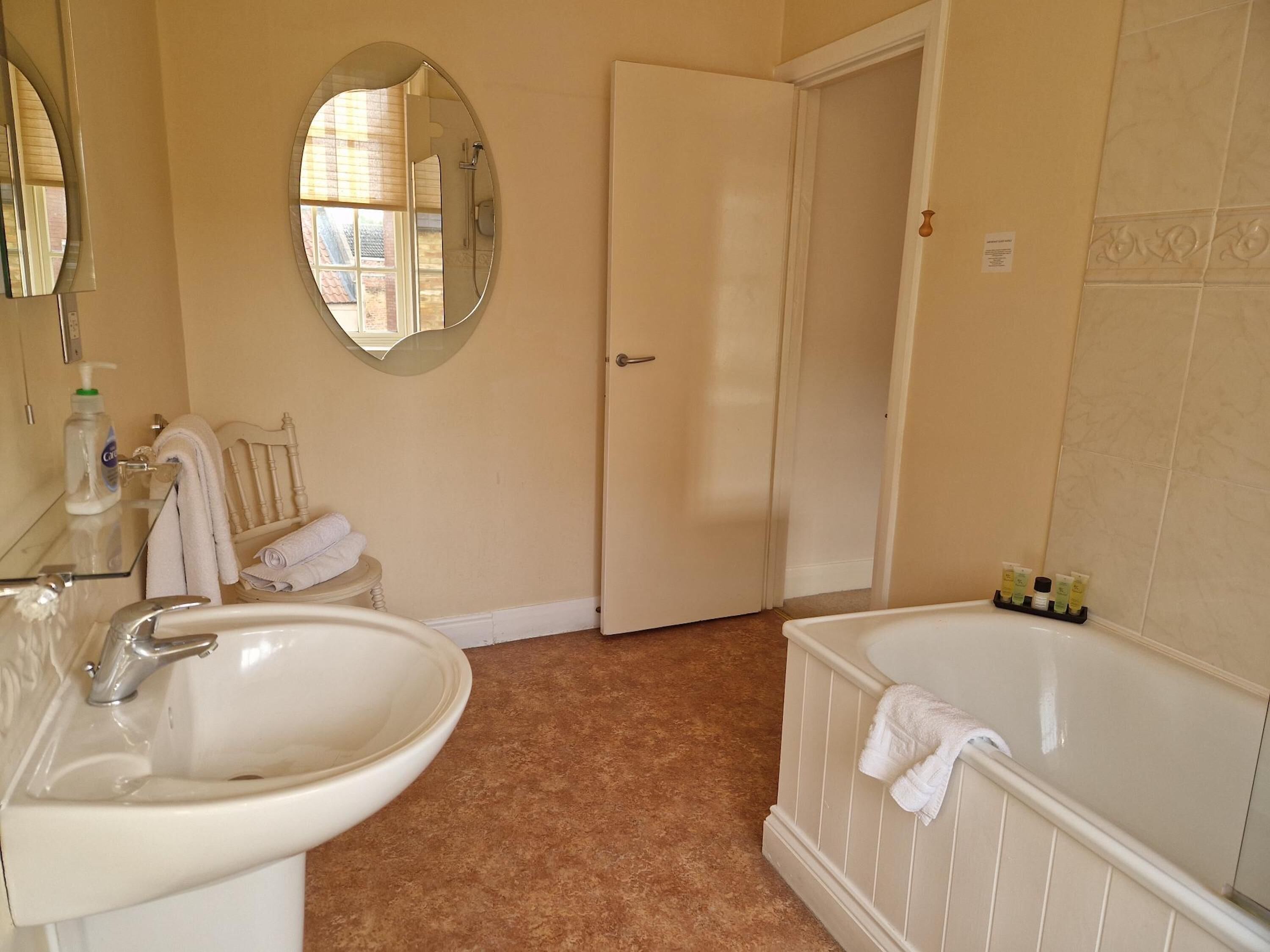 A bathroom with a sink, mirror, and bathtub.