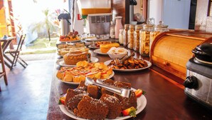 A buffet table with various food items and a vintage radio. - Pousada do Enildo (São Miguel dos Milagres)