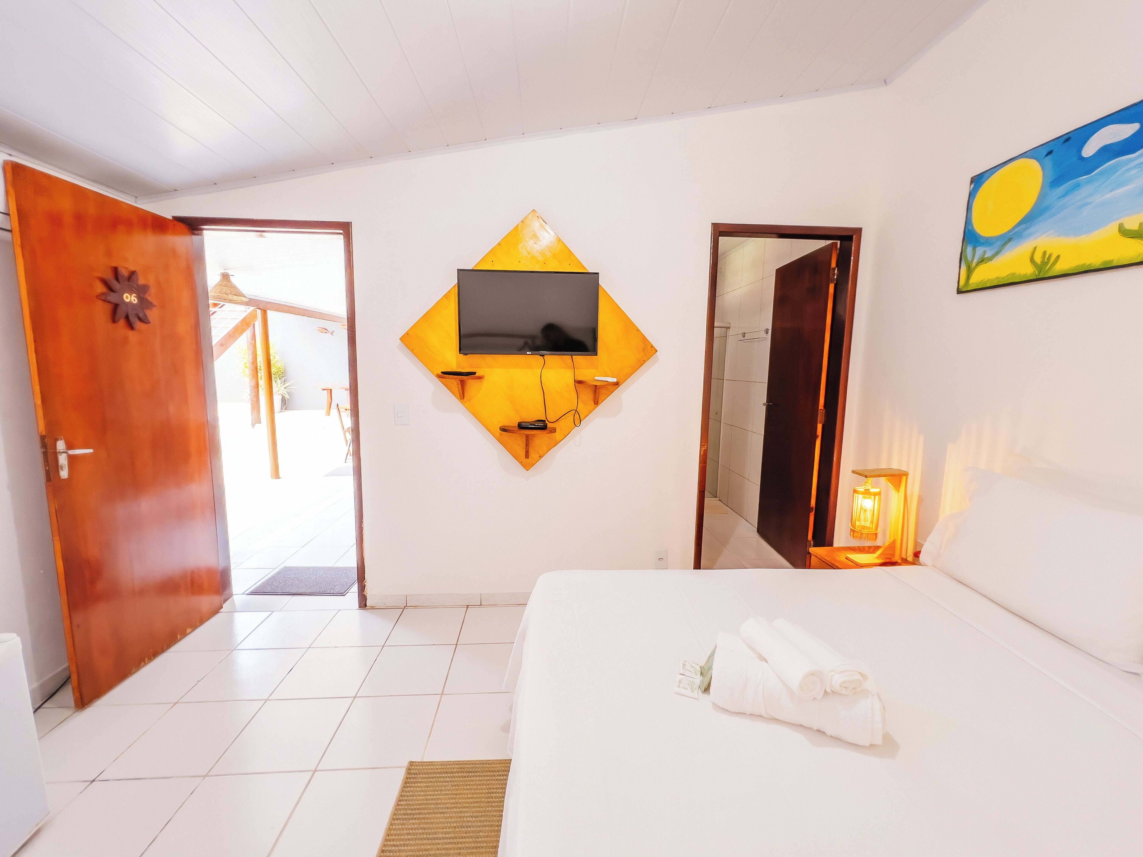 Een hotelkamer met een bed, een aan de muur bevestigde televisie, een deur en een schilderij.