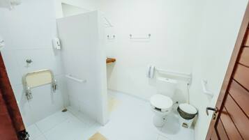 Un baño con azulejos blancos, inodoro, bidé, barandilla y toallero.