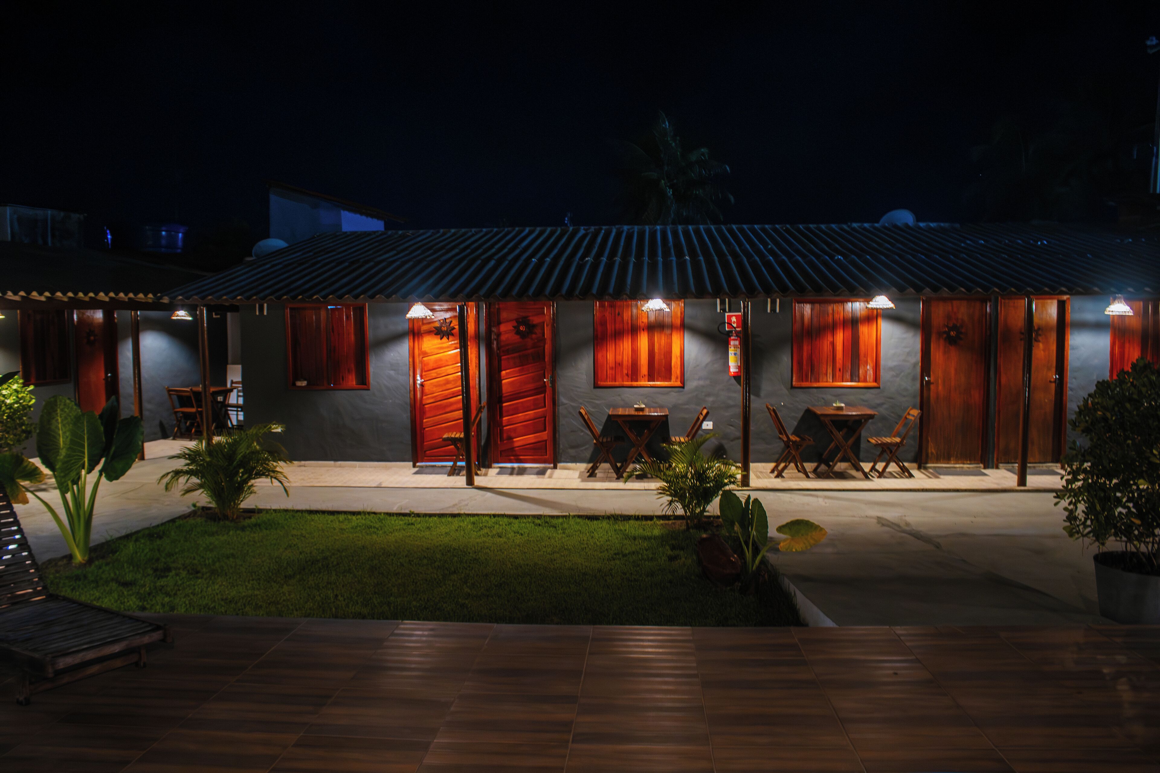 A building with a tiled roof, wooden doors, and a small outdoor seating area with tables and chairs.