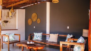 A room with a wooden bench, a wooden table, and a wall with woven wall art. - Pousada do Enildo (São Miguel dos Milagres)