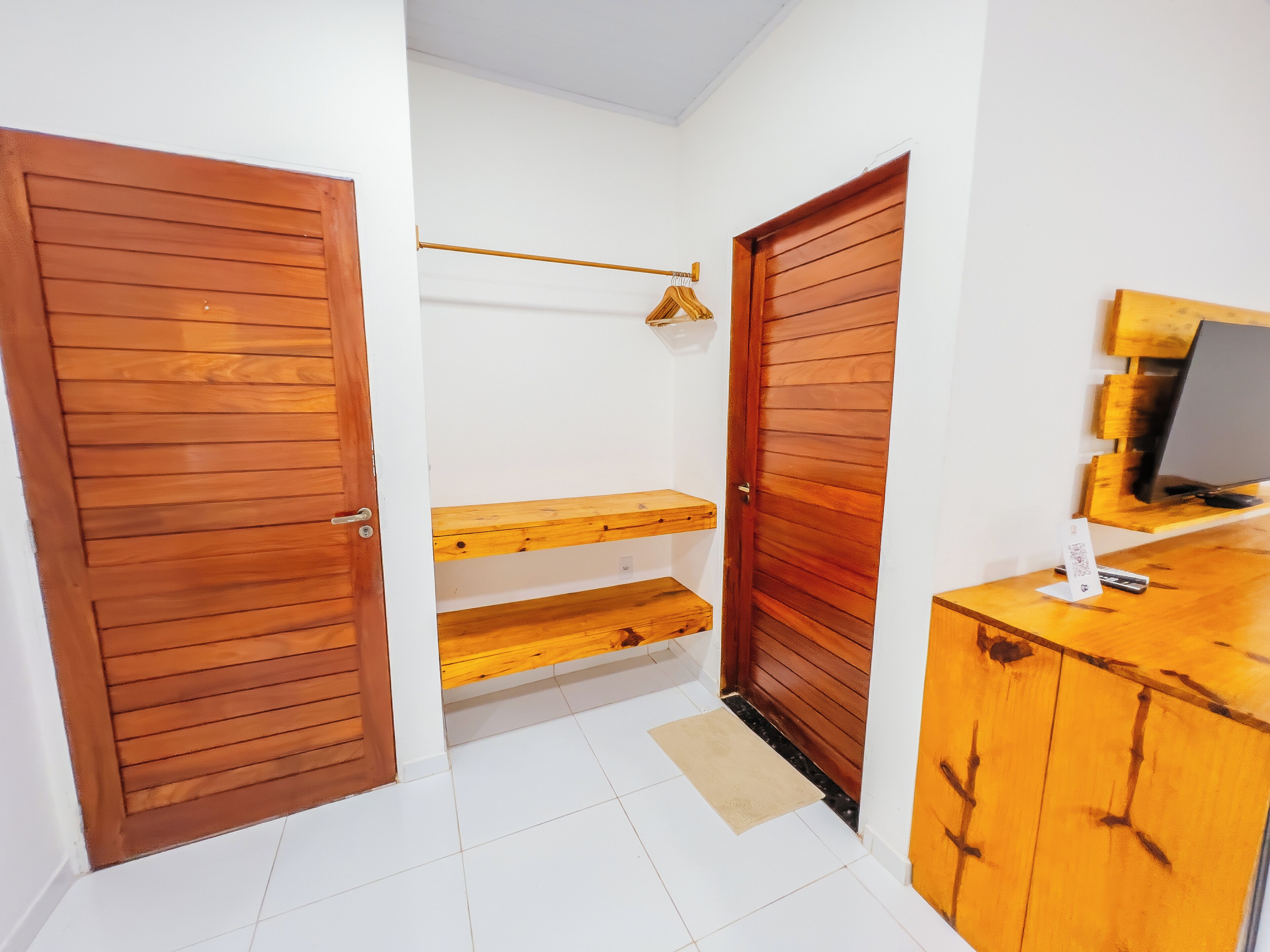 Ein Korridor mit Holztüren, einem Holzregal, einem Schreibtisch mit Computer und einem kleinen Teppich.