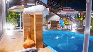 A poolside area with a hot tub, lounge chairs, and umbrellas. - Pousada do Enildo (São Miguel dos Milagres)