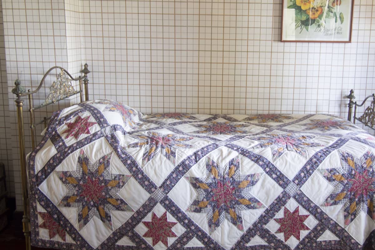 Ein Bett mit einer Quilldecke in einem Raum mit Wabenmuster-Wänden.