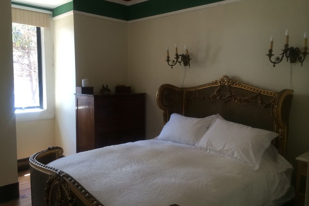 Ein Schlafzimmer mit einem Holzbett, einem Schminktisch und einem Fenster mit Jalousien.