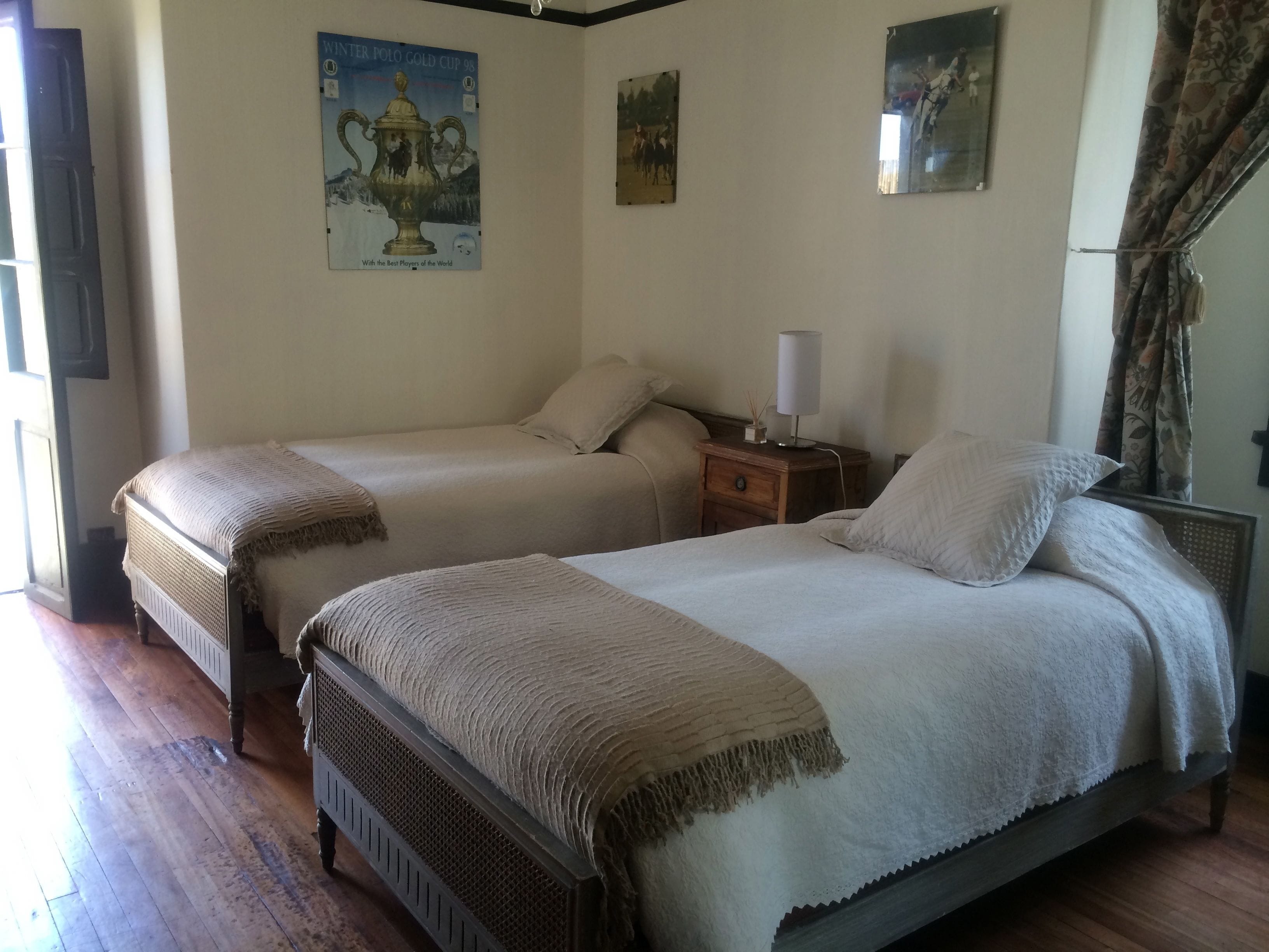 Un dormitorio con dos camas individuales, una mesita de noche con lámpara y un cartel en la pared.