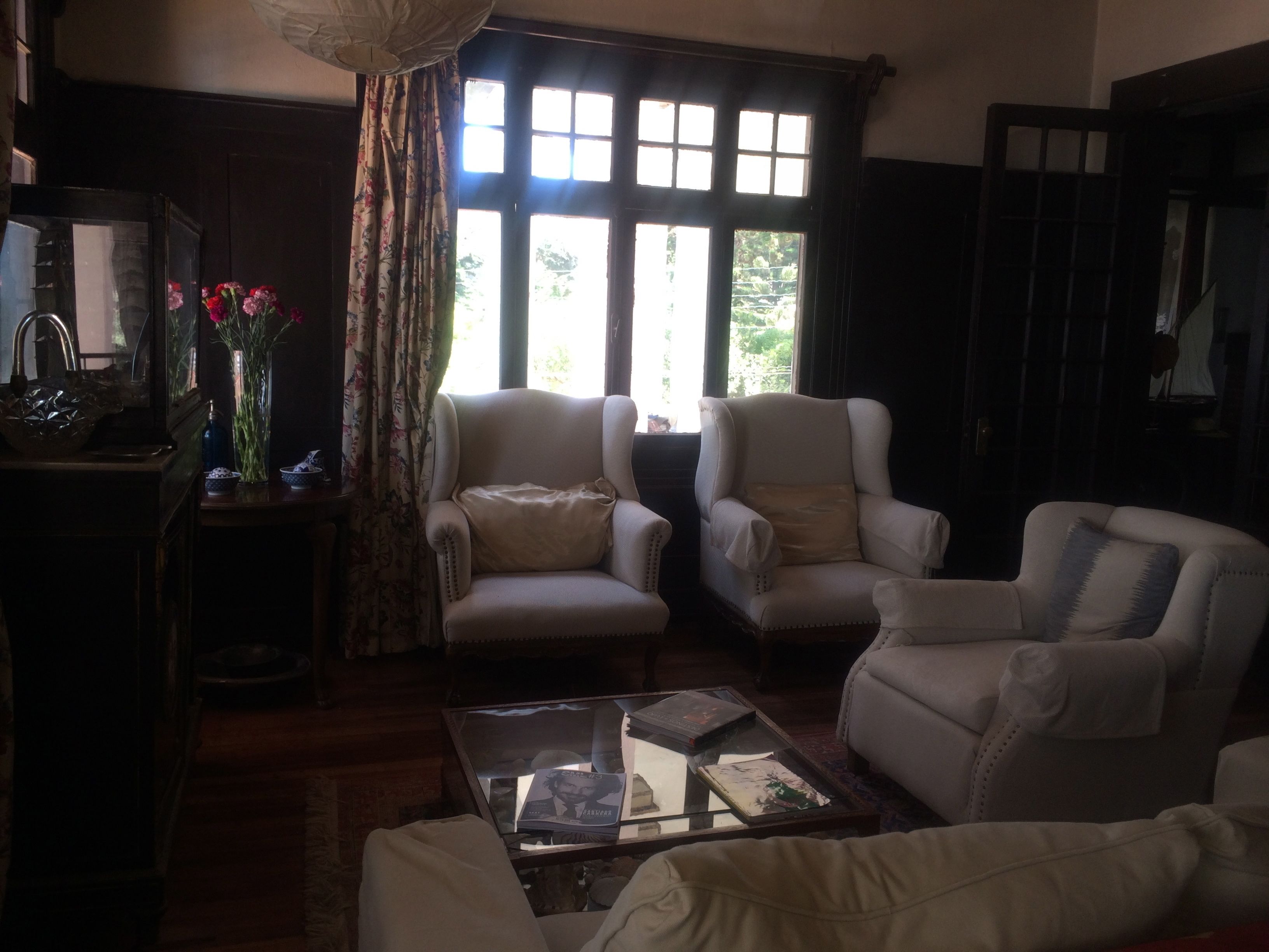 Una sala de estar con dos sillones, una mesa de centro y un ventanal con cortinas.