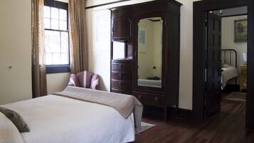 Een slaapkamer met een bed, een kast, een spiegel en een deur naar een andere kamer.