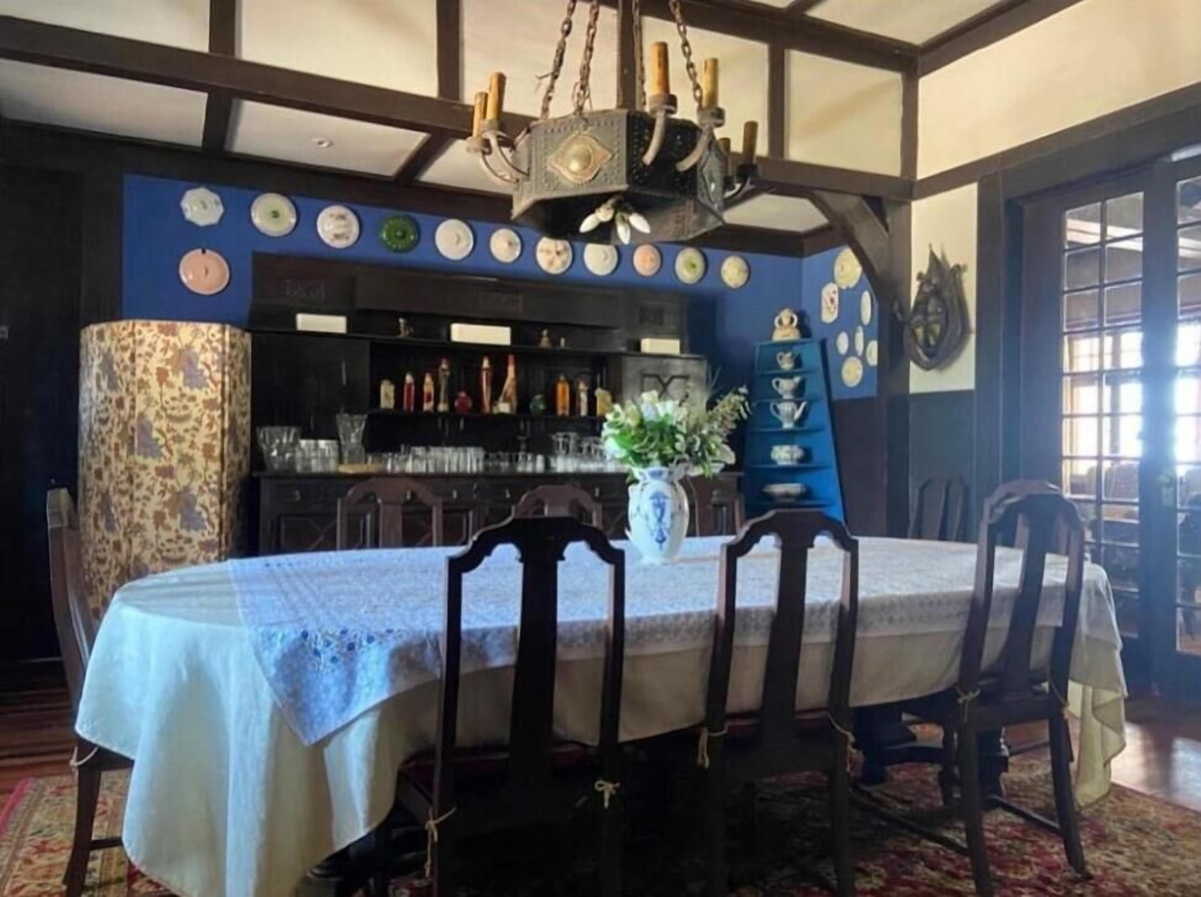 A dining area with a table set for four, a chandelier, and a bar area with bottles in the background.