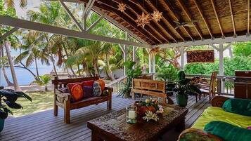Un espacio al aire libre cubierto con muebles de madera, una mesa con vela y vista al océano.