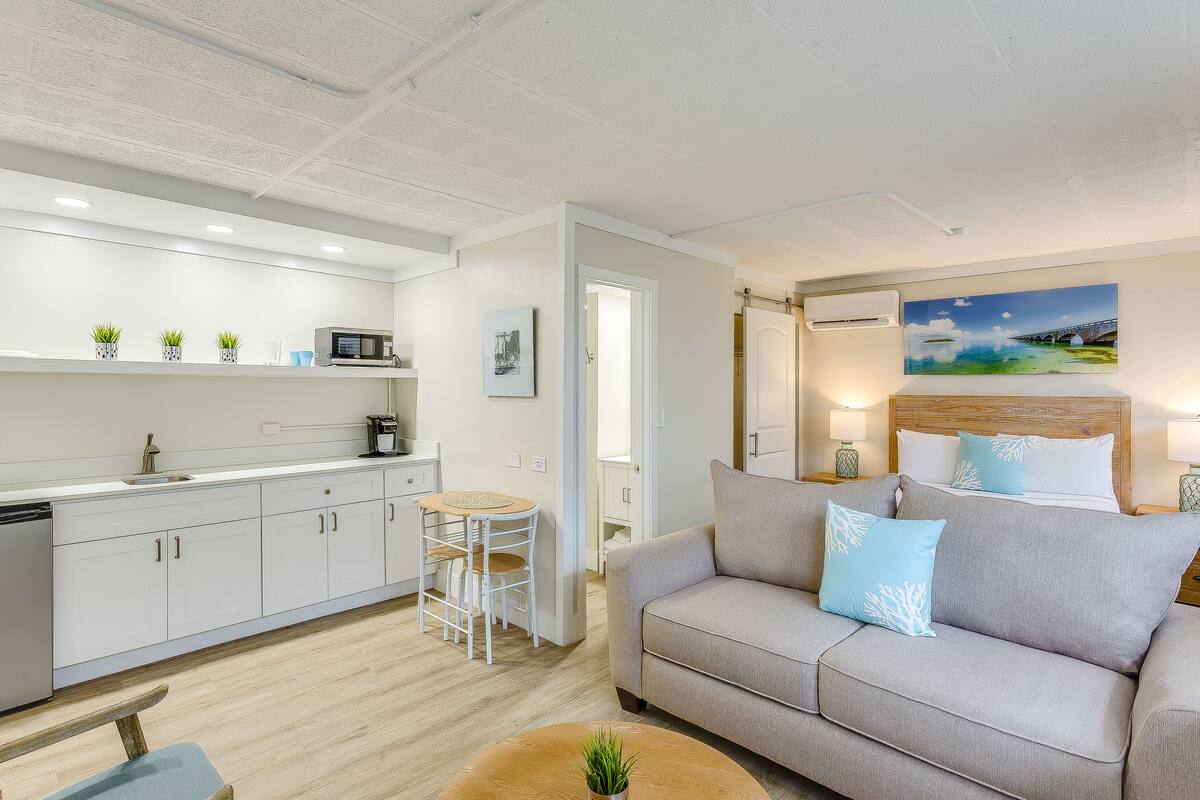 A modern living room with a sofa, a coffee table, and a kitchen area with cabinets and a microwave.