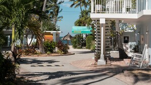 A beachfront property with a white building, a balcony with a white railing, and palm trees. - La Jolla Resort (Islamorada)