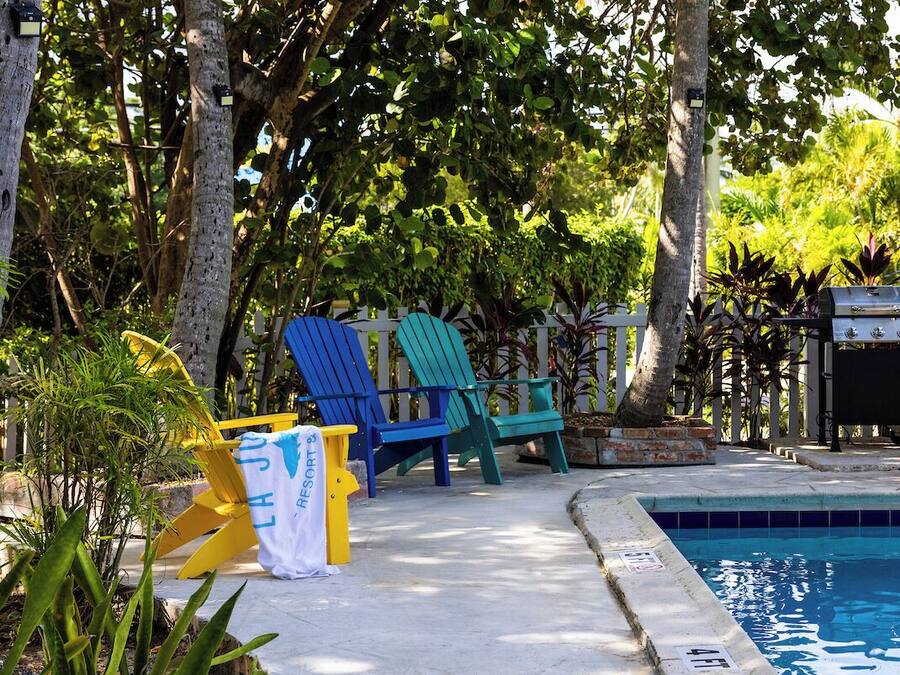 A poolside area with a pool, lounge chairs, and a grill.