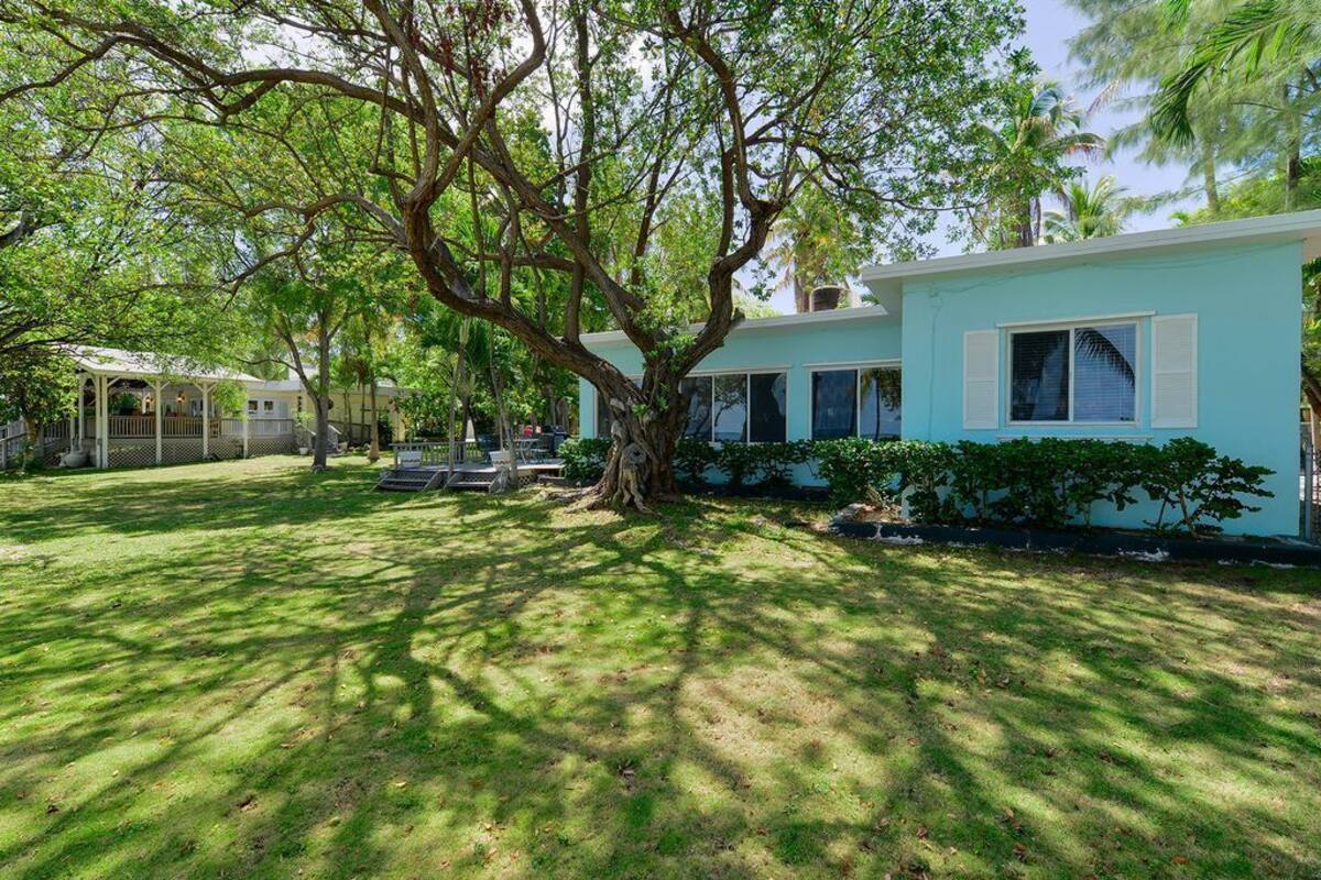 A two-story house with a large tree in the front yard.